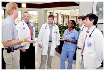 A group of trainees and staff talking in a hospital corridor